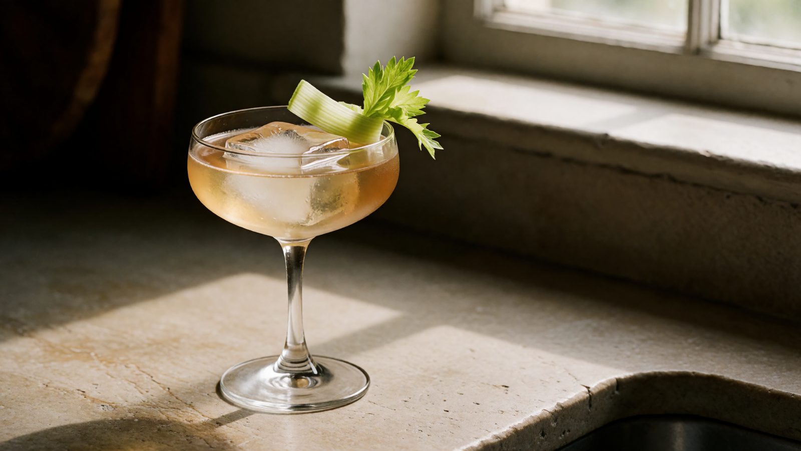 A crystal-clear Bloody Mary made with clarified tomato water in a coupe glass, garnished with a celery ribbon